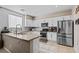 Well-lit kitchen with white cabinetry, a stainless steel refrigerator, and an island at 7017 Pink Flamingos Pl, North Las Vegas, NV 89084
