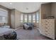 A spacious bedroom featuring a cozy seating area, dresser, and view of the outdoors at 7171 Willow Moss Ct, Las Vegas, NV 89148