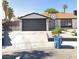 Charming single-story home with a black two car garage door and an automatic gate at 7285 Pinebrook Cir, Las Vegas, NV 89147