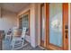 Welcoming front porch featuring two rocking chairs, a rustic barrel table, and a wood-framed glass door at 7301 Bachelors Button Dr, Las Vegas, NV 89131