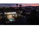 Two story home with a balcony overlooking the pool, and exterior lighting, with mountain views in the distance at 74 Innisbrook Ave, Las Vegas, NV 89113