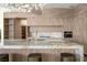 Bright kitchen features a large waterfall island, bar seating, modern lighting, and light wood cabinetry at 74 Innisbrook Ave, Las Vegas, NV 89113