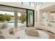 Bright living room featuring a curved sofa, stone coffee table and seamless access to the outdoor pool and patio at 74 Innisbrook Ave, Las Vegas, NV 89113
