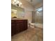 A well-lit bathroom with a dark wood vanity, tile floors, a glass-enclosed shower, and a toilet at 861 Majestic Ridge Ct, Henderson, NV 89052