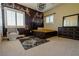 A well-lit bedroom featuring a stylish bed, chair, dresser, area rug, and two windows with shutters at 861 Majestic Ridge Ct, Henderson, NV 89052