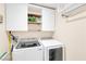 Bright laundry room with white cabinets, wood shelves, and modern Samsung washer and dryer at 9171 Denver Sky Ave, Las Vegas, NV 89149