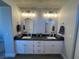 A well-lit bathroom featuring dual sinks, dark countertops, and modern light fixtures at 9328 Jumpin Juniper Ave, Las Vegas, NV 89129