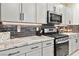 Modern kitchen with stainless steel appliances, stone countertops, and dark backsplash at 10190 Natural Anchor St, Las Vegas, NV 89166