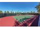 Well-maintained tennis court with vibrant colors, surrounded by a secure fence and lush greenery at 10239 Premia Pl, Las Vegas, NV 89135