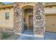 Charming stone-accented home entrance featuring a decorative wood door and cozy bench at 1049 Via Saint Lucia Pl, Henderson, NV 89011