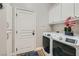 Bright laundry room with white washer and dryer, storage cabinets, and wood flooring at 1049 Via Saint Lucia Pl, Henderson, NV 89011