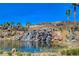 Scenic view of community water feature with a waterfall cascading into a serene lake, surrounded by lush vegetation and palm trees at 116 Juliette Pointe Ln, Henderson, NV 89011