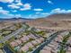 Expansive aerial view of the community showcasing the homes and roads near mountainous terrain under a sunny, cloudy sky at 12240 Old Muirfield St, Las Vegas, NV 89141