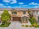 Aerial view of a tan two-story house with green shutters and a brown garage door, nicely landscaped with a brick driveway at 12240 Old Muirfield St, Las Vegas, NV 89141