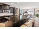 Gourmet kitchen with dark cabinets, stainless appliances, and a large island with seating, open to a spacious dining area at 12240 Old Muirfield St, Las Vegas, NV 89141