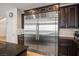 Sleek stainless steel refrigerator integrated with dark wood cabinetry, enhancing the modern and efficient kitchen design at 12240 Old Muirfield St, Las Vegas, NV 89141