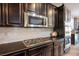 Well-appointed kitchen with dark wood cabinets, stainless steel appliances, granite countertops, and white subway tile backsplash at 12240 Old Muirfield St, Las Vegas, NV 89141