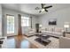 Staged living room with hardwood floors, a white sofa, a ceiling fan, and a large window for natural light at 2141 Twickenham Pl # A, Las Vegas, NV 89108