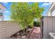 Side yard features small tree, brick lined walkway and a brick wall behind foliage at 2161 Avalon Dr, Laughlin, NV 89029