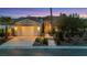 Attractive front exterior with a well-lit garage, stone walkway, and beautiful landscaping at dusk at 2785 Soft Horizon Way, Las Vegas, NV 89135