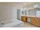 Bathroom showcasing soaking tub, double sinks, wood cabinetry, and large mirrors at 3932 Maldive Isle Ct, Las Vegas, NV 89129