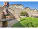 Landscaped backyard with artificial turf, wooden swing, and colorful umbrella at 4813 Stony Hill St, North Las Vegas, NV 89031