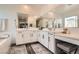 Bright bathroom featuring a double vanity, large mirrors, white cabinets, and soaking tub at 4813 Stony Hill St, North Las Vegas, NV 89031