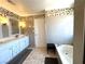 Bathroom featuring double sinks, white cabinets, decorative tiling, and a soaking tub at 5255 Autumn Sky Rd, Las Vegas, NV 89118