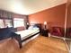 Bedroom with wood floors, a queen bed, dark furniture and an orange accent wall at 5255 Autumn Sky Rd, Las Vegas, NV 89118