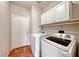 View of the laundry room with side-by-side washer and dryer, cabinets, and tile floors at 5952 Long Bay St, Las Vegas, NV 89148