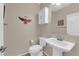 Well-lit half bath featuring a pedestal sink, toilet, storage cabinet, and decorative mirror at 6733 Fast Brook Ct, North Las Vegas, NV 89084