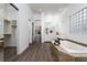 Bathroom with a soaking tub, tiled surround, dual sinks, a walk-in closet and a glass block window at 68 Isleworth Dr, Henderson, NV 89052