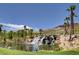 Lush landscape with a tiered waterfall flowing into a pond surrounded by palm trees and desert vegetation at 8 Reverie Heights Ave, Henderson, NV 89011