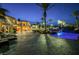 Elegant backyard at dusk featuring a custom rock pool, patio seating, manicured landscaping and lighting at 8280 Via Olivero Ave, Las Vegas, NV 89117