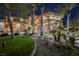 Elegant two-story home featuring a grand entrance, lush landscaping, and mature palm trees at night at 8280 Via Olivero Ave, Las Vegas, NV 89117