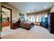 Spacious main bedroom featuring a large window, dark wood furniture, and neutral carpet at 8280 Via Olivero Ave, Las Vegas, NV 89117