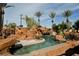 Luxurious pool with rock formations, palm trees, and serene water elements creating a tropical paradise at 8280 Via Olivero Ave, Las Vegas, NV 89117