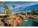 Tranquil pool with rock formations and a waterfall, surrounded by lush landscaping and towering palm trees at 8280 Via Olivero Ave, Las Vegas, NV 89117