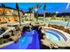 Night view of luxurious pool with custom rock waterfall and hot tub feature with tennis court in background at 8280 Via Olivero Ave, Las Vegas, NV 89117