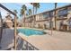 Exterior view of a sparkling community pool surrounded by lush palm trees and modern buildings at 8426 Sluman Ct, Las Vegas, NV 89128