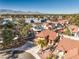 Aerial view of a home with a red tile roof, mature landscaping, and mountain views in the distance at 8932 Beach Front Dr, Las Vegas, NV 89117