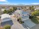 Aerial view of a two-story home with a spacious driveway, detached garage, lush lawn, pool, and mountain views at 9435 Westwind Rd, Las Vegas, NV 89139