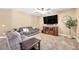 Comfortable living room featuring neutral tones, plush carpeting, and a large flat-screen television at 9435 Westwind Rd, Las Vegas, NV 89139