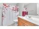 Clean bathroom with a white vanity, stylish cherry blossom shower curtain, and neutral color scheme at 10415 Scarpa St, Las Vegas, NV 89178