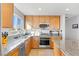 A modern kitchen features wooden cabinets, granite countertops, and stainless steel appliances at 10415 Scarpa St, Las Vegas, NV 89178