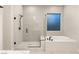 Bright bathroom featuring modern glass shower and separate tub beneath a window at 12160 Harris Summit Ave, Las Vegas, NV 89138