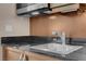 Close-up of a stainless steel sink and cooktop on a dark countertop with wood cabinets at 125 E Harmon Ave # 809, Las Vegas, NV 89109