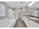 Bright bathroom featuring white cabinets, dual sinks, a tiled tub/shower combo, and wood-look tile flooring at 12816 Alcores St, Las Vegas, NV 89141