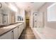 Bright bathroom featuring double vanity with granite counters, shower, soaking tub and tile floors at 12816 Alcores St, Las Vegas, NV 89141