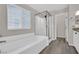 A well-lit bathroom featuring a soaking tub with a glass-enclosed shower and a window with blinds at 12816 Alcores St, Las Vegas, NV 89141